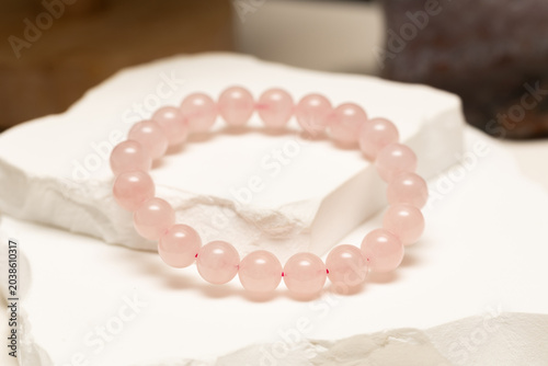 Tableau sur toile Rose quartz bracelets rest on a white stone surface