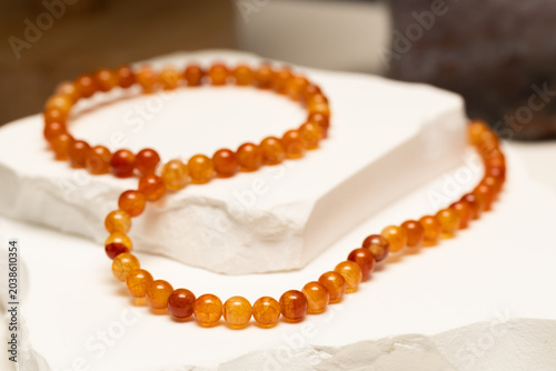 Cracked agate beads are arranged on a white stone surface. These stones are used to make bracelets and necklaces for people who enjoy wearing unique jewelry.