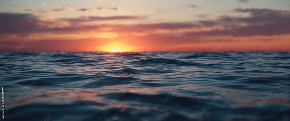 Obraz premium Glowing sky and soft golden light illuminating calm ocean waves at twilight