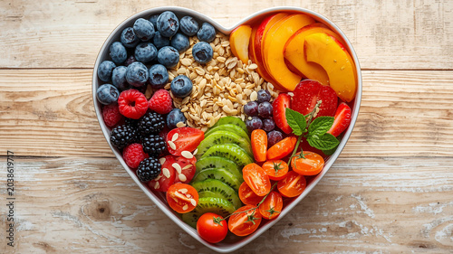 Healthy breakfast meal in heart shaped bowl with berries oatmeal and fresh fruit.