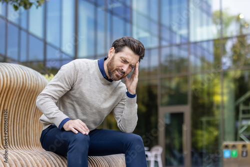 Stressed man suffering from headache pain outdoors