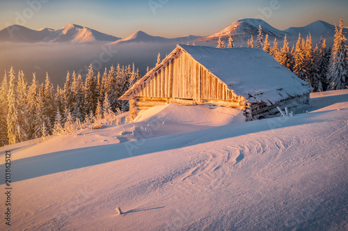 Konstfotografi Abandoned wooden cabin in snowy winter mountains at sunrise