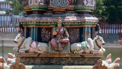 Photography Colorful Hindu temple sculpture with seated goddess flanked by reclining bull on
