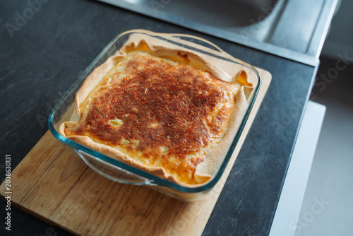 Homemade Leek Quiche with baked cheese crust in a glass plate cooling on cutting board