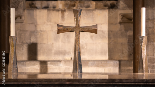 Foto Bronze cross on stone altar flanked by two tall candle holder inside cathedral