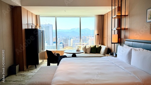 Luxury hotel room with a comfortable bed and large floor-to-ceiling window overlooking Sapporo cityscape, Hokkaido.