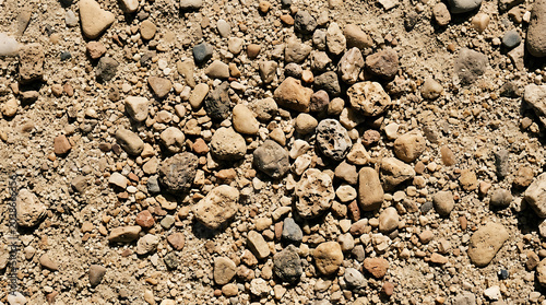 High angle shot of natural dry ground texture featuring scattered pebbles small rocks and coarse sand in earthy tones for organic background design
