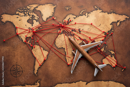 A model of a passenger plane over the continents, the routes are marked with pins, with red threads between them