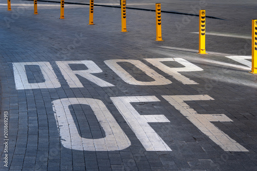 Billede på lærred Large drop off zone pavement marking on a paved urban area with yellow safety bollards, suitable for transportation, parking, passenger pickup and traffic management concepts