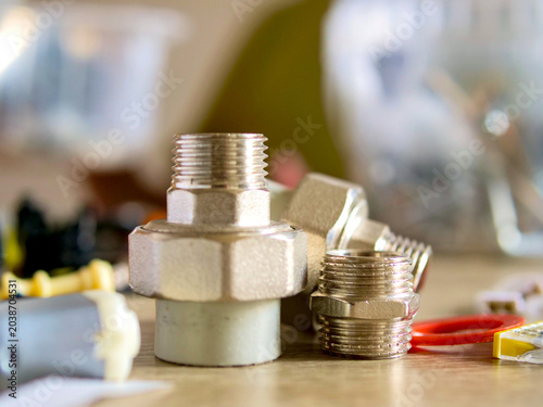 Plumbing brass union fitting and threaded pipe connectors close up on workshop table; conceptual for home plumbing repair, diy hardware maintenance, renovation construction and engineering