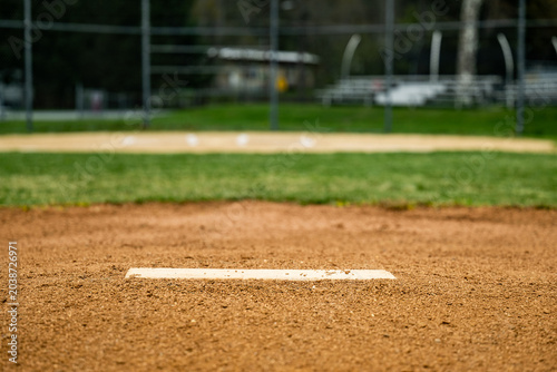 Foto Ground-level view of the infield of a baseball field with the empty white plate on the pitcher's mound stretching out horizontally across the foreground of the shot