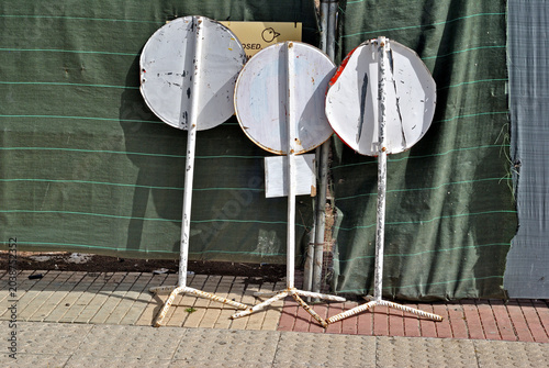 Photos Three Old Circular Road Signs on Stands Beside Wall on Caribbean Street
