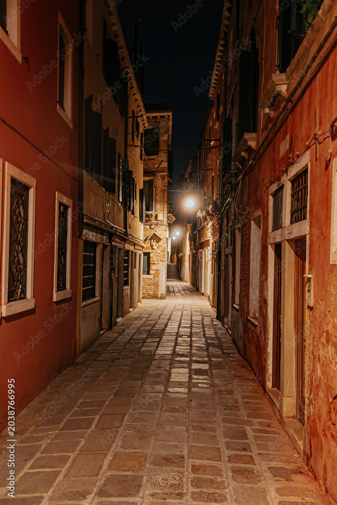 Fototapeta premium Empty Venice street at night with soft lights and historic architecture