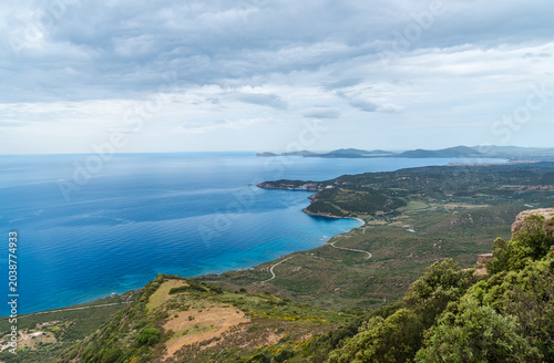 Panoramic view of the western coast of Sardinia, Italy, with the Mediterranean Sea and Capo Caccia in the background.