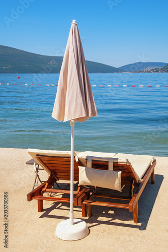 Beach vacations. Coast of Bay of Kotor, chaise lounges and beach umbrella. Montenegro, Tivat