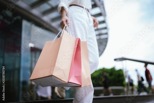 Foto Close-up of a shopper carrying colorful shopping bags outdoors, symbolizing retail spending, consumer lifestyle, fashion purchases, and modern shopping experiences