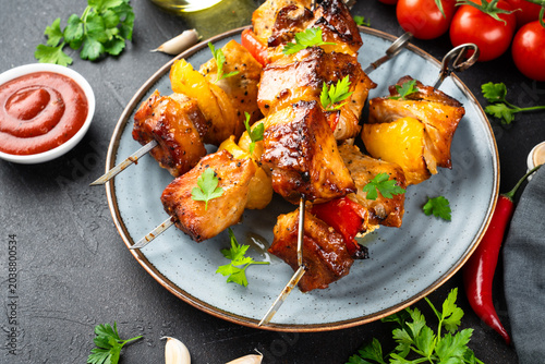 Photos Grilled shish kebab, Grilled meat skewers with vegetables and herbs on black background