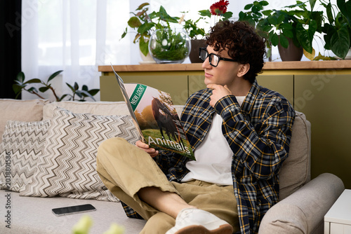 Foto Curly young man enjoys a blissful moment reading in his modern apartment