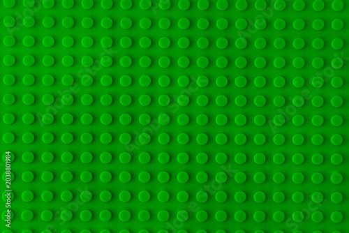 Green plastic plate building blocks baseplate texture, top view toy brick board pattern construction background.