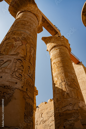 Epic Karnak temple ancient Egyptian architecture hypostyle hall panorama. 
Cinematic low angle view of historic Luxor sandstone columns, 
carved pharaoh hieroglyphs bas relief and blue sky.
