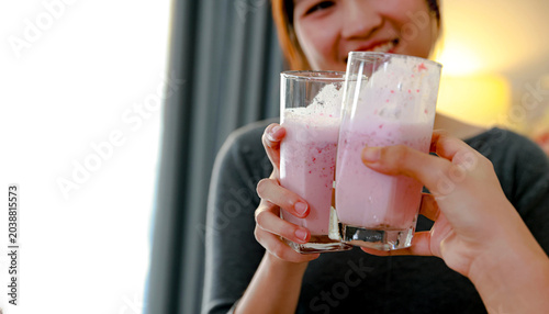 Bild auf Leinwand Two teenage Asian girls happily make refreshing strawberry and banana smoothies in their home kitchen creating unique and delicious recipe