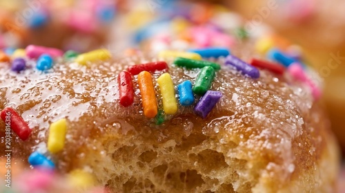 Macro view of a glazed donut with colorful rainbow sprinkles on top