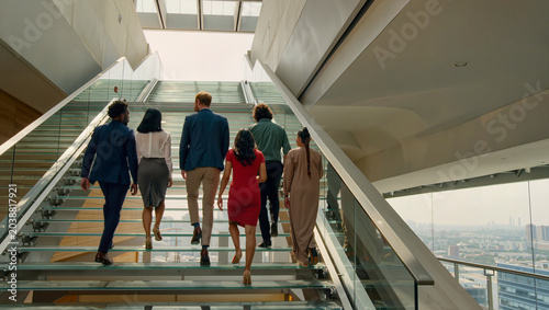 Professionals walking up modern glass staircase in office building