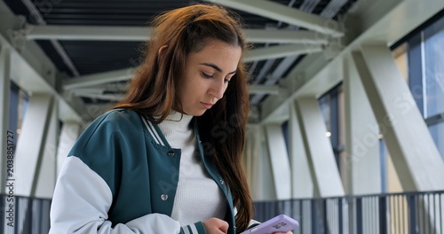 Bild auf Leinwand Closeup young woman texting on smartphone, wearing green and white jacket, soft