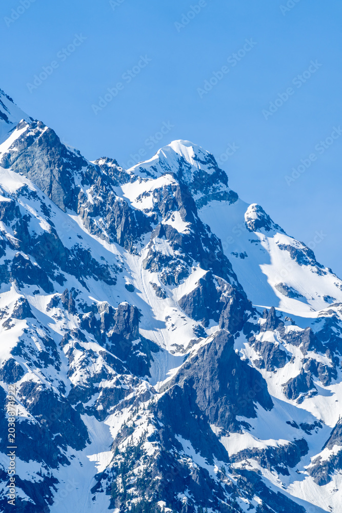 Obraz premium Snow Covered Rocky Mountain Peaks Under Blue Sky