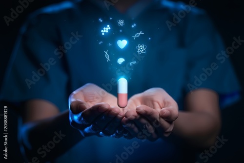 Person in blue shirt holds glowing red and white capsule with floating medical symbols