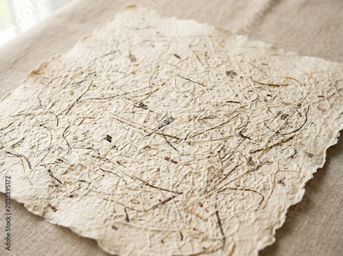 Handmade recycled paper with deckled edges, textured artisanal botanical parchment on linen fabric, rustic organic stationery for wedding invitations