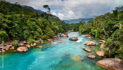 vibrant turquoise waters flow through lush green forests and rocky formations in the breathtaking cano cristales river a natural wonder in colombia s sierra de la macarena