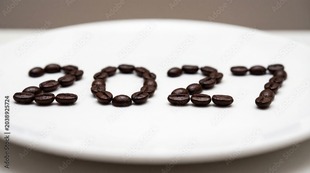 Naklejka premium Coffee beans arranged as 2027 on white plate with shallow focus for breakfast ritual cafe branding roasted aroma seasonal menu morning lifestyle concept cozy banner cafe menu promotion