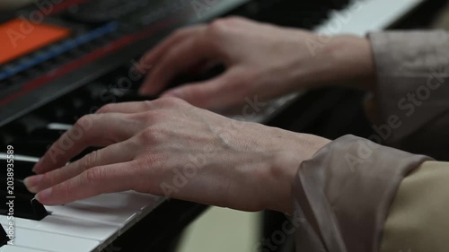 female pianist hands on black and white synthesizer keyboard, close-up view, young woman playing piano, professional musician