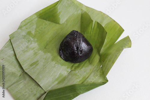 Kue bugis ketan hitam, traditional dessert from Indonesia, made from black glutinous rice flour dough, filled with grated coconut, wrapped in a banana leaf