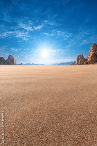 Golden sandy landscape under a bright sun, with distant rocky formations and a clear blue sky, creating a serene and tranquil atmosphere perfect for nature-related themes,