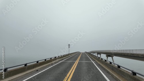 Driver’s perspective crossing the bridge to Assateague Island, Maryland, surrounded by dense fog with limited visibility ahead and on both sides, creating a moody and atmospheric coastal travel scene