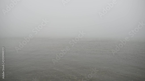 A calm inland lake at Assateague Island enveloped in dense fog, with still water blending into the mist and obscuring the distant shoreline, creating a quiet and atmospheric coastal wetland scene