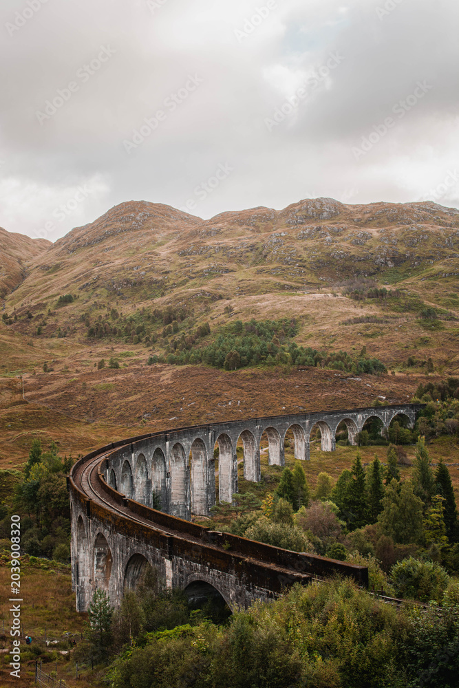 Naklejka premium The historic Glenfinnan Viaduct surrounded by lush green hills, Scottish Highlands