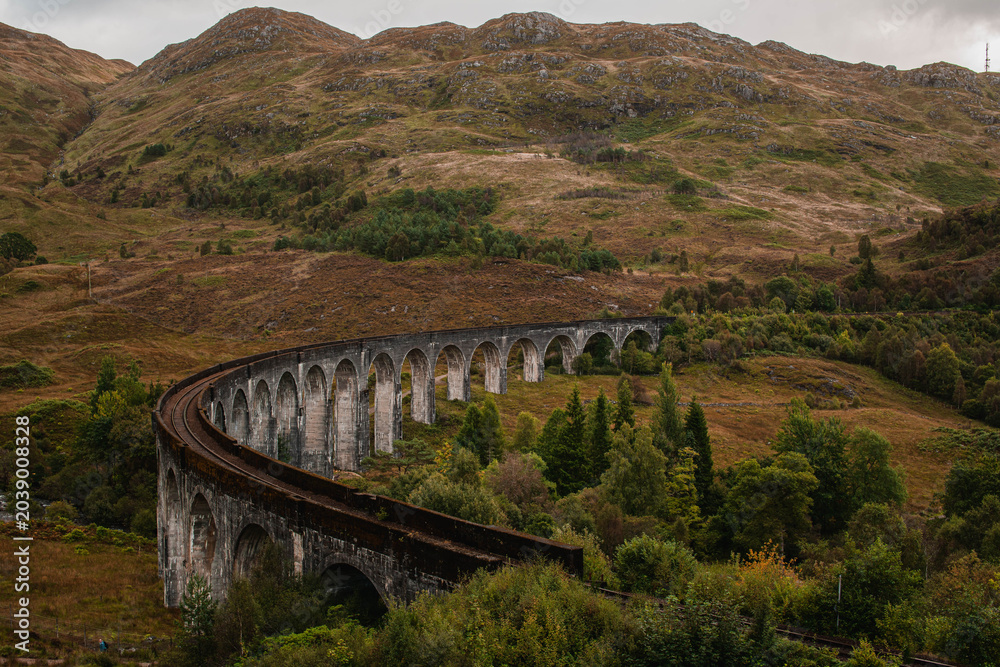 Naklejka premium The historic Glenfinnan Viaduct surrounded by lush green hills, Scottish Highlands