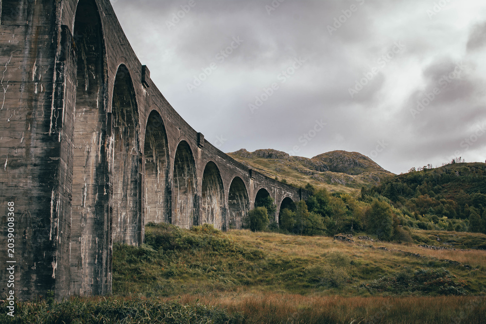 Naklejka premium The historic Glenfinnan Viaduct surrounded by lush green hills, Scottish Highlands
