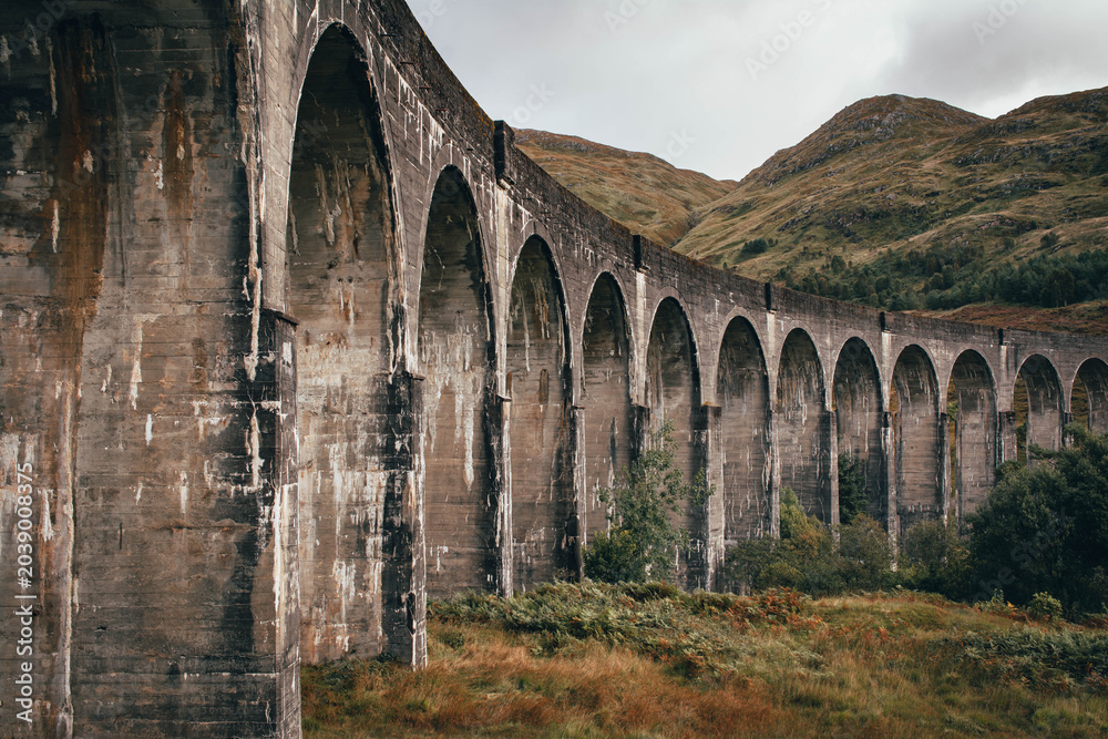 Naklejka premium The historic Glenfinnan Viaduct surrounded by lush green hills, Scottish Highlands