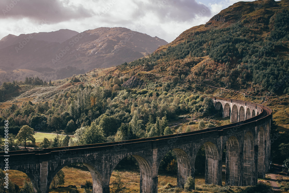 Naklejka premium The historic Glenfinnan Viaduct surrounded by lush green hills, Scottish Highlands