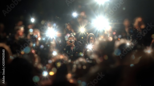 Crowd flashes cameras, paparazzi event, celebrity premiere, blurred audience, bright lights