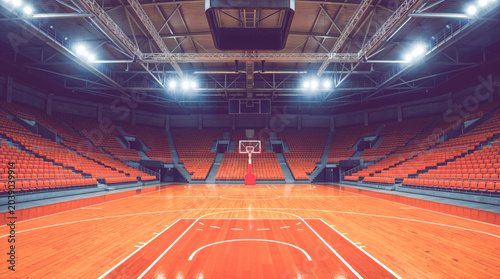 Empty basketball court under bright lights in indoor arena