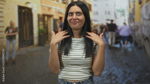 Vászonkép Woman crossing arms with hands held forward in a refusal gesture on a crowded cobblestone street with pedestrians and buildings; disgust rejection