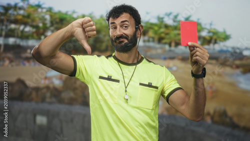 Canvastavla Referee man in yellow shirt shows red card and thumbs down gesture with whistle and headset visible on street; discipline authority