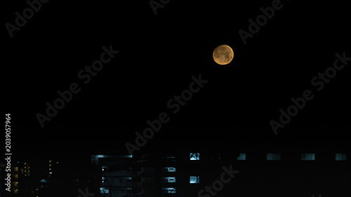 夜空に浮かぶ満月と都市夜景