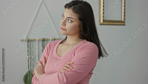 Canvastavla Woman in pink sweater with folded arms looking sideways at macrame wall hanging in studio; quiet contemplation
