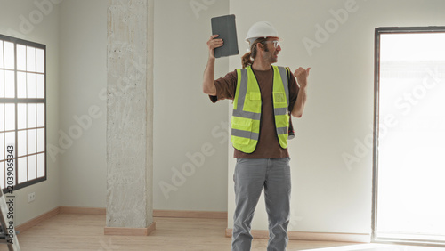 Fotografie Man architect holds tablet aloft with one hand and hand on hip in building; site inspection confidence
